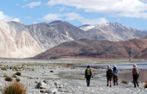 Ladakh : 4 silhouettes marchent aux pieds de montagnes dans le lointain