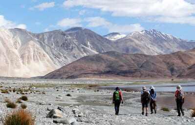 Ladakh : 4 silhouettes marchent aux pieds de montagnes dans le lointain