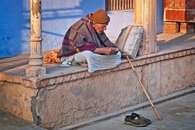 Inde : Un vieil homme avec une couverture sur les épaules, est assis sur une terrasse.