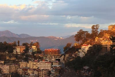 Inde : Au coucher du soleil, une ville en pente avec des montagnes au loin