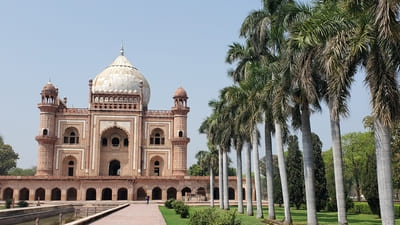 Inde, New Delhi : Derrière une rangée de cocotiers, un bâtiment posé sur des arcades est surmonté d'un dôme blanc