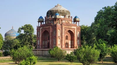 Inde, New Delhi : Un bâtiment des grès rouge avec des dômes abimés teintés de bleu, est posé dans un parc arboré