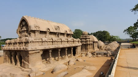 Inde - Un bâtiment de pierres ocres surmonte des colonnes. Une allée passe à côté