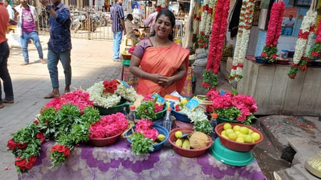 Inde du Sud : une femme en sari, tient un stand de fleurs et d'offrandes