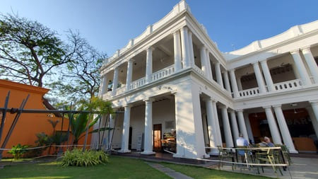 Inde : Un bâtiment colonial à colonnes et étage est pris en photo du jardin
