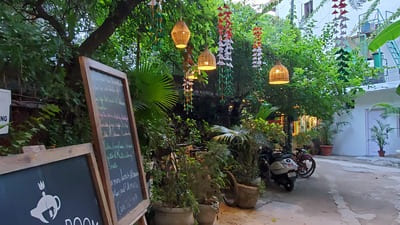 Inde, New Delhi : Des abat-jours sont au-dessus de plantes en pots. Une ardoise avec un menu de restaurant, est posé devant