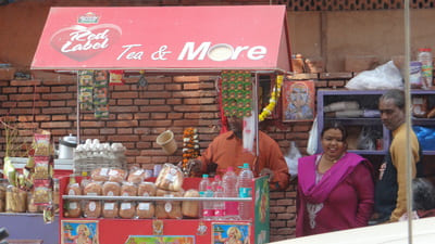 Inde, New Delhi : Un stand de rue qui vend des bouteilles d'eau et des gâteaux avec une femme qui sourie à côté