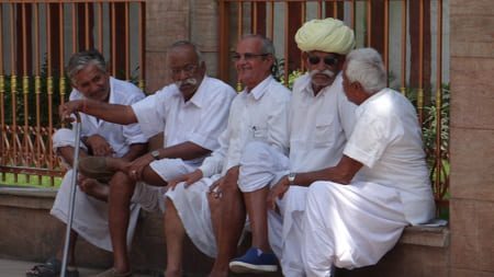Inde : Des hommes âgés habillés de blanc, discutent les uns à côté des autres, assis sur un muret