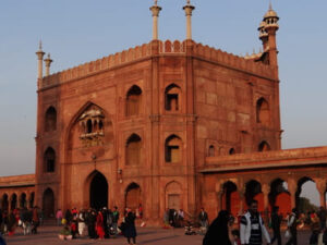 Inde, New Delhi - Bâtiment en grès rouge avec 4 tourelles. Des gens se promène devant.