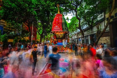 Inde : Une fête dans la rue avec des silhouette floues marchent derrière un char avec une tourelle recouverte de tissu rouge