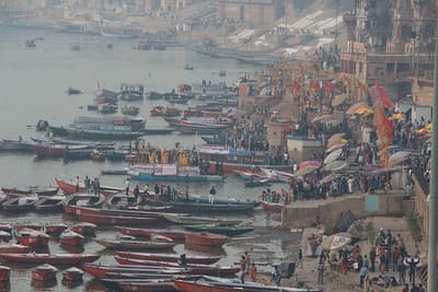 Inde, Varanasi : Dans la brume, des barques sont amarrées aux quais où attend la foule