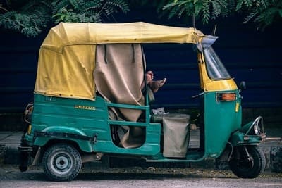 Inde : Tuk-tuk (triporteur) indien avec deux pieds qui dépassent d'une personne qui dort dedans