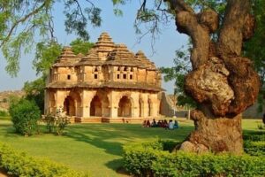 Inde : Un bâtiment de pierres ocres avec arcades, est au centre d'une pelouse