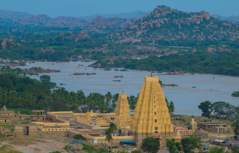 Inde : Des tours d'un temple sont au bord d'une rivière, dans un paysage de rochers et de verdure