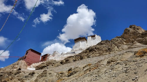 Ladakh : Un monastère blanc se détache sur le ciel ennuagé, en haut d'un rocher