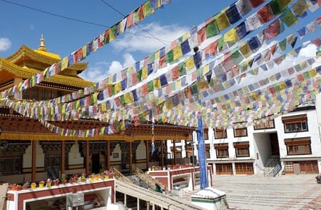 Ladakh : Des drapeaux de prières flottent dans le ciel au-dessus d'une cour, en partant d'un bâtiment