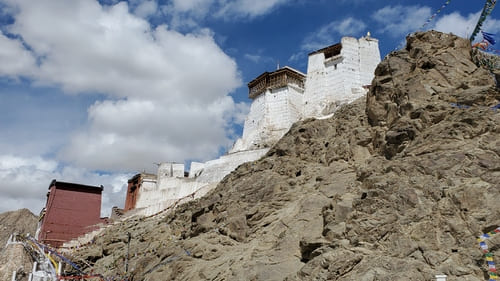 Ladakh : En haut de rochers, un bâtiment blanc et un autre rouge se détachent dans le ciel