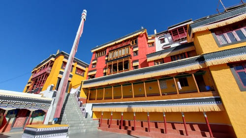 Ladakh : Des bâtiments rose et jaunes se détachent sur un ciel bleu turquoise