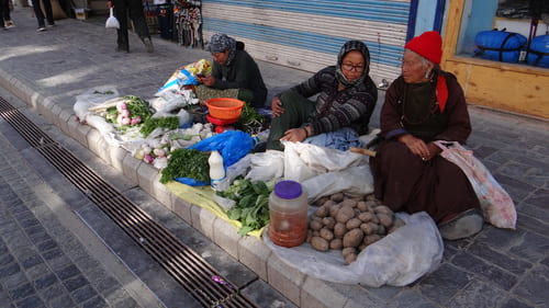 Ladakh : 3 vieilles dames, sont assises par terre derrière leur étalage de légumes