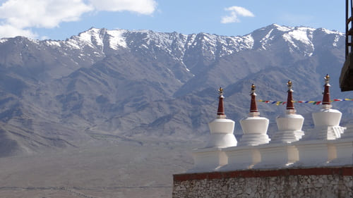 Ladakh : Au 1er plan des stupas sur un socle avec une chaîne montagneuse et enneigée au loin